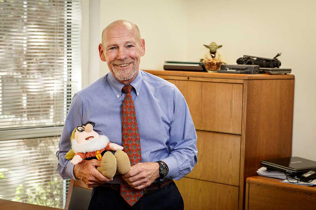Dr. 照片中，他在办公室里拿着一个毛绒玩具.